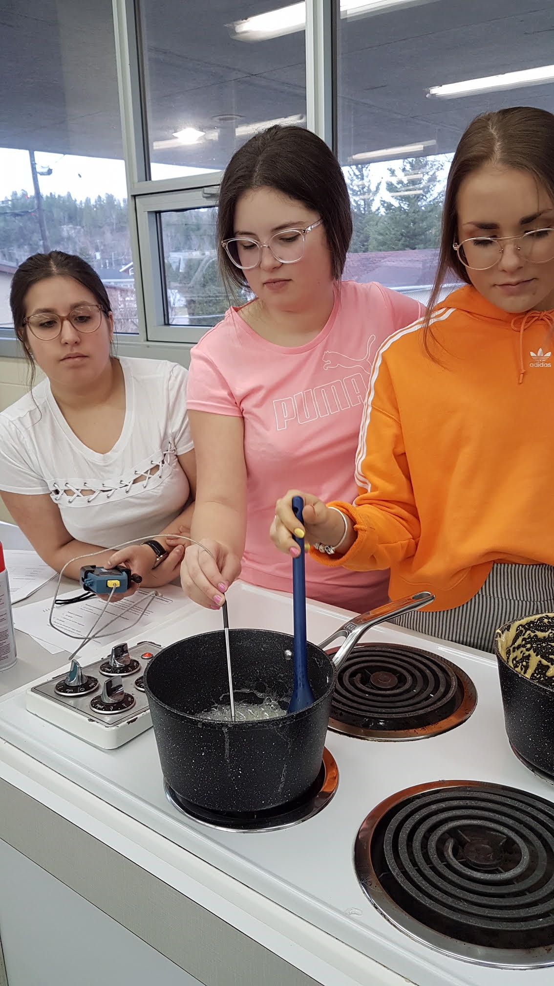 Trois étudiantes du secondaire de Charles-Gravel concentrées sur leur casserole dans laquelle une préparation bout.