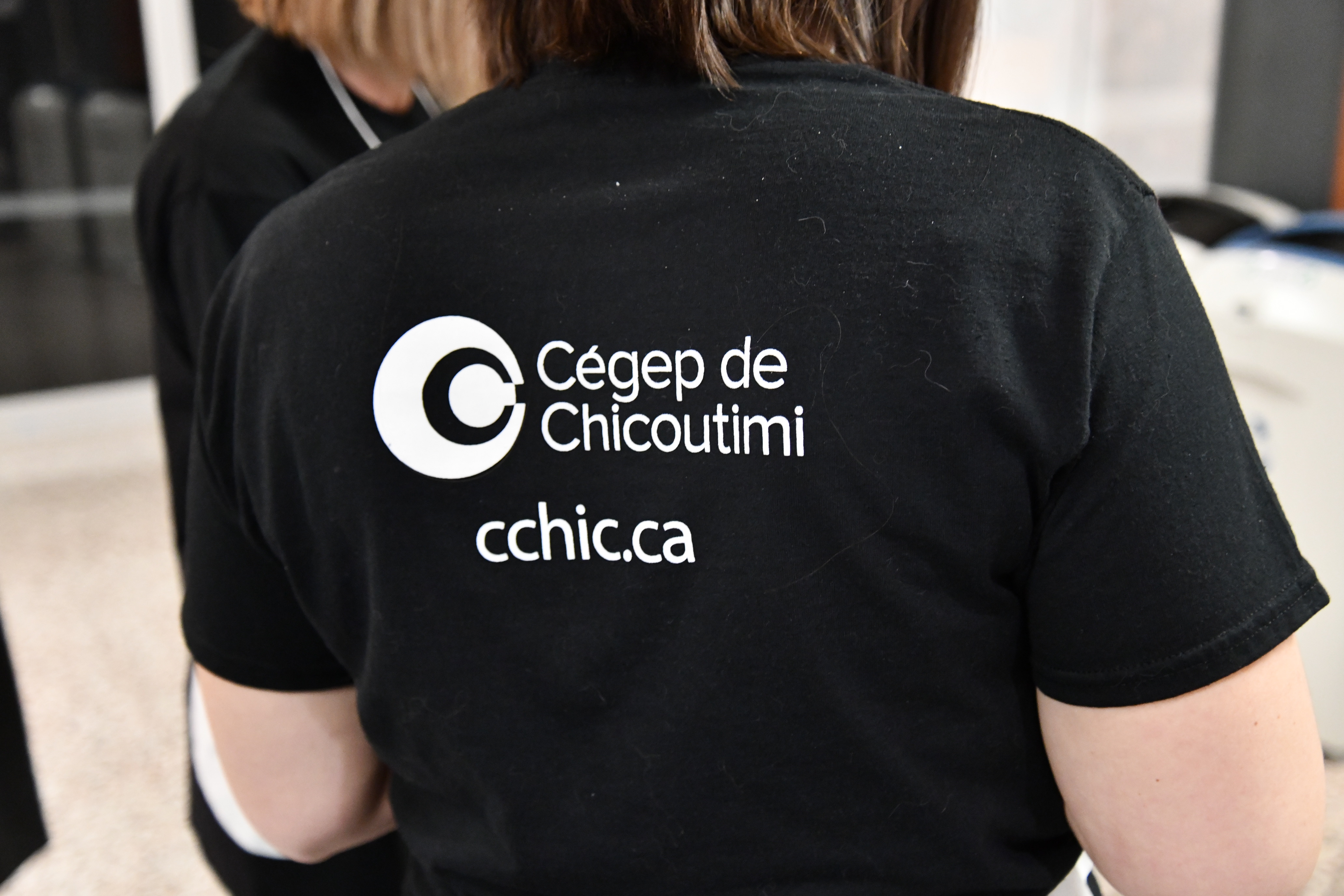 Le dos du tee-shirt d'une encadrante avec le logotype du Cégep de Chicoutimi.