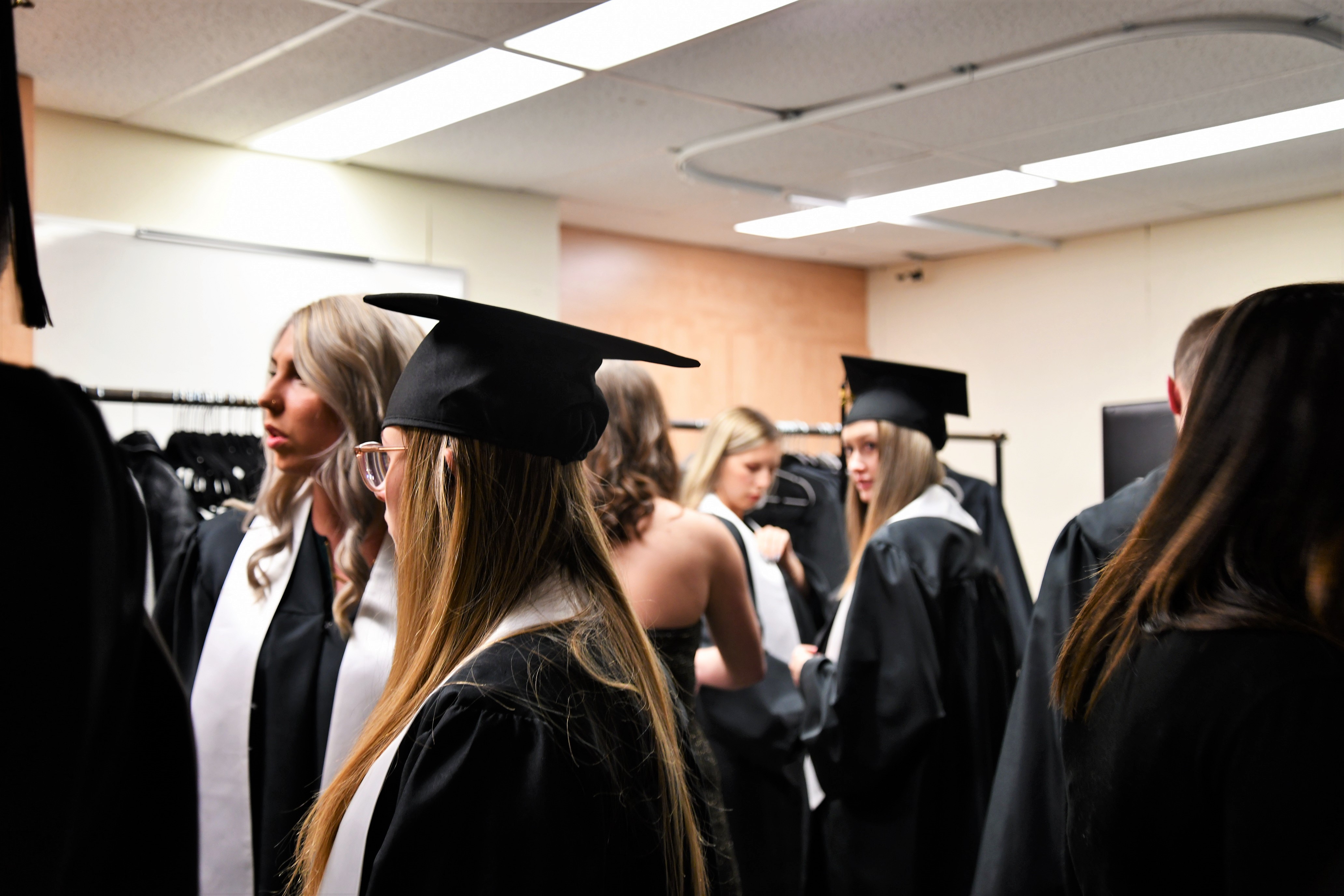 Photo des étudiants dans le vestiaire pour mettre leur toge et chapeau.